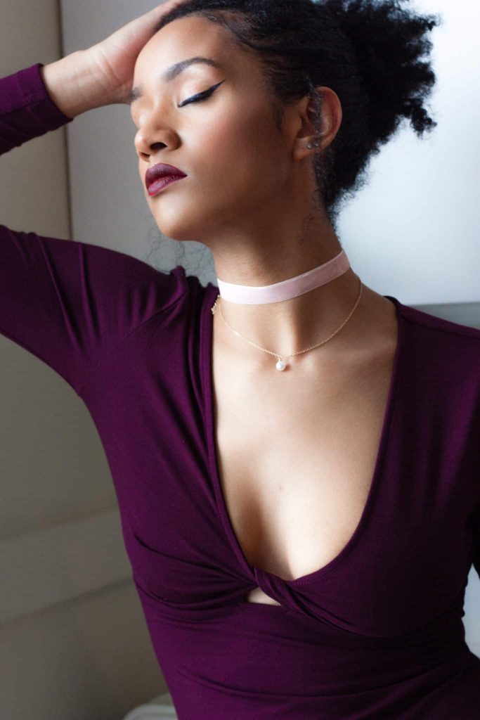 Black woman in contemplation | Low-cut simple dress for a night out, with pink choker (valentine's day look?)