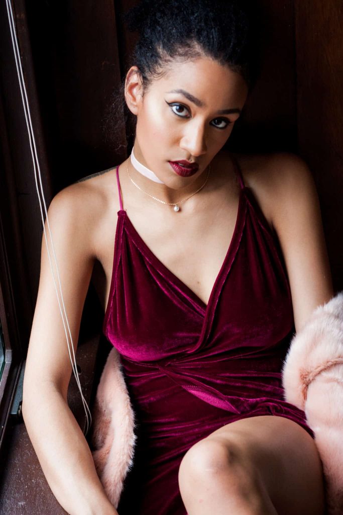 Black woman modelling wine V cut velvet dress. with choker. for a luxury valentine's day look