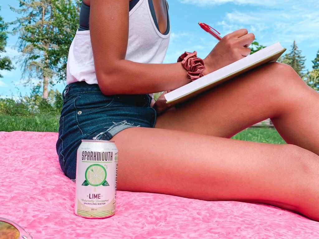 Black Canadian Blogger, Comfy Girl with Curls writing in the park with her SPARKMOUTH Sparkling Water in Lime. (Close up of can)