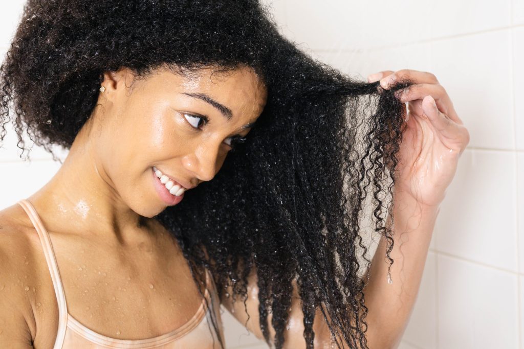 Natural Hair Blogger, ComfyGirlCurls holding up freshly clarified hair in the shower.